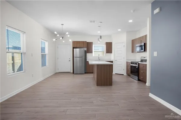 a kitchen with stainless steel appliances kitchen island granite countertop a refrigerator oven a sink dishwasher and white cabinets with wooden floor