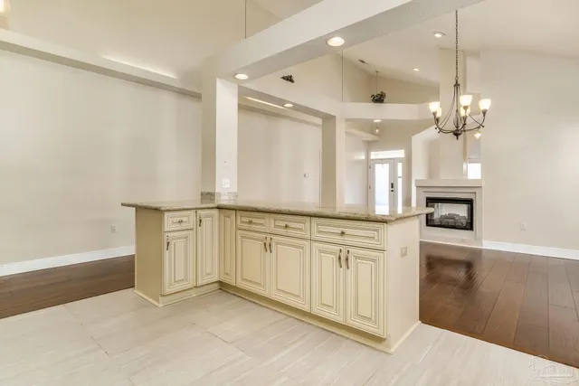 a large white kitchen with a sink and chandelier