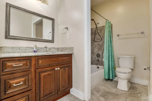 a bathroom with a granite countertop toilet sink and mirror