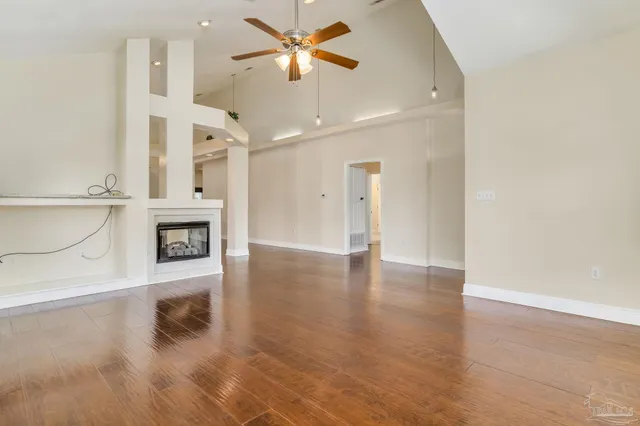 a view of a livingroom with a fireplace a ceiling fan and wooden floor