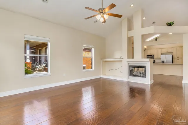 a view of an empty room with a kitchen and wooden floor