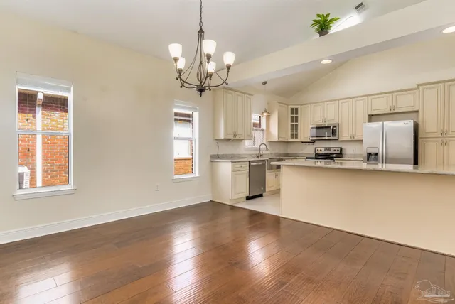 a view of a kitchen with stainless steel appliances granite countertop a refrigerator a stove a sink dishwasher a microwave oven with cabinets and wooden floor
