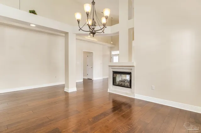 a view of an empty room with wooden floor fireplace and a window