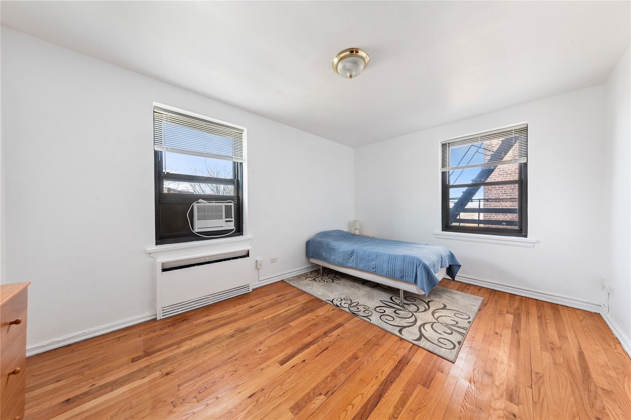 73-62 Bell Boulevard, Unit 4K Queens, NY 11364 - Photo 5 of 16 Bedroom featuring hardwood / wood-style flooring, cooling unit, and baseboards