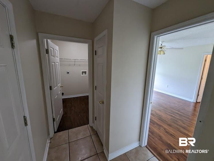 12971 Labradors Run Foley, AL 36535 - Photo 15 of 23 Hallway with tile flooring, leading to an interior laundry area with wire shelving and wood-finish flooring, and a separate room with wood-finish flooring and a ceiling fan