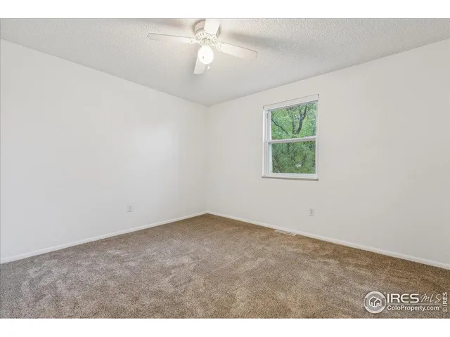an empty room with a chandelier fan and windows