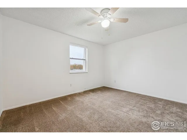 an empty room with a chandelier fan and windows