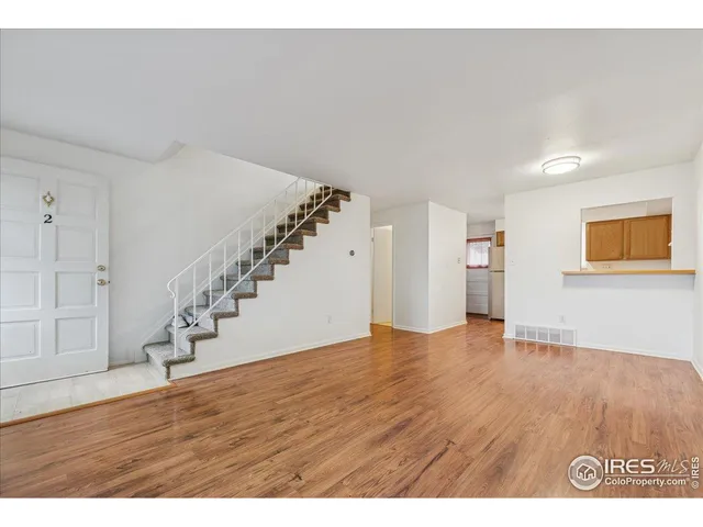 a view of an empty room with wooden floor and stairs