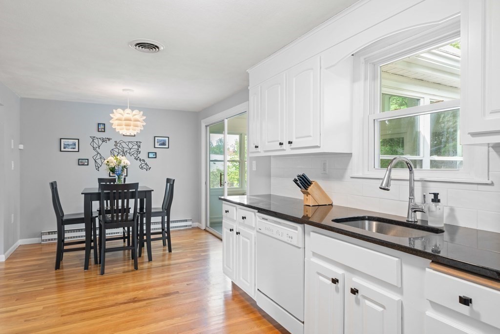 4 Rayner Circle Stoneham, MA 02180 - Photo 7 of 27 a kitchen with granite countertop a dining table chairs and white cabinets