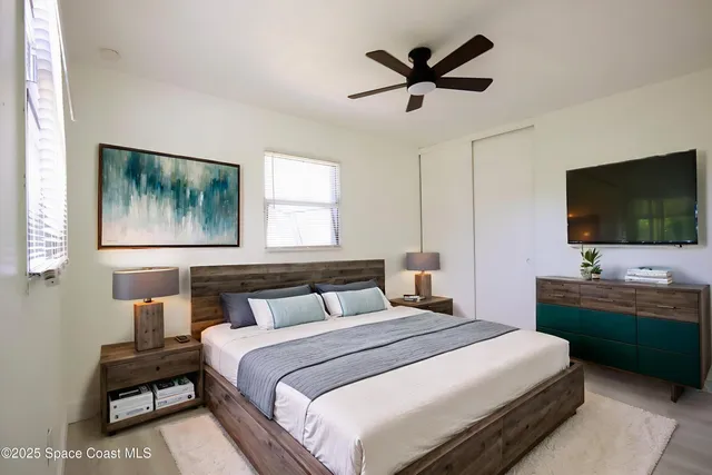 a bedroom with a bed a window and a flat screen tv