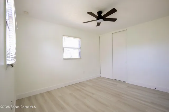 an empty room with wooden floor and ceiling fan