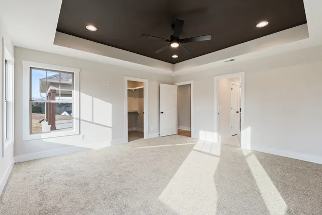 a view of an empty room with glass door and chandelier fan