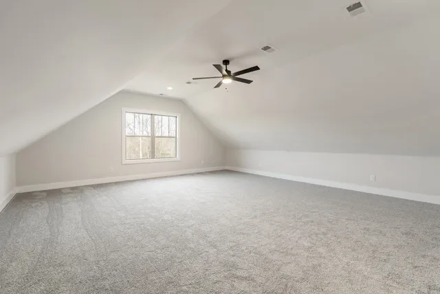 an empty room with chandelier fan and windows