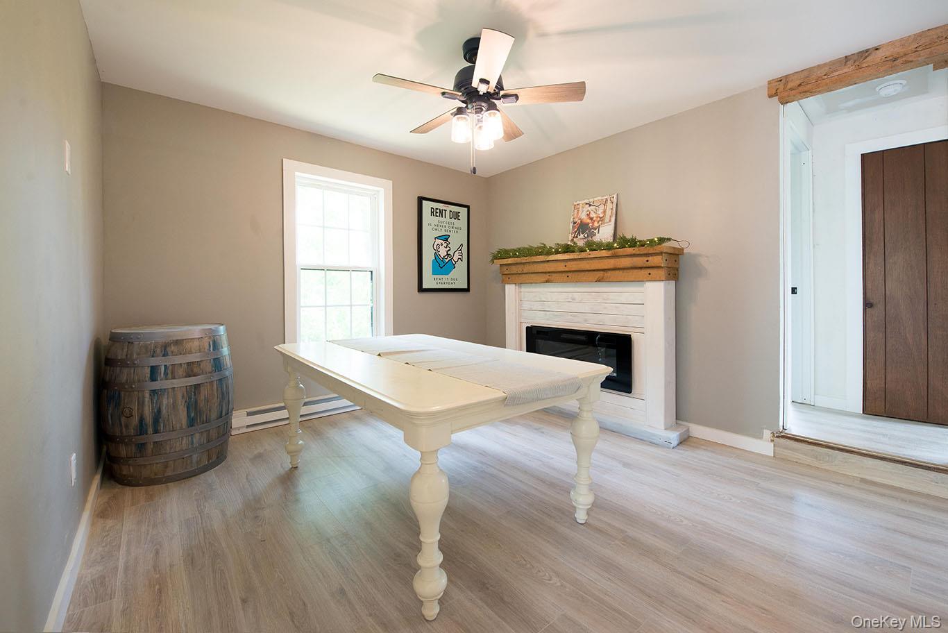 1132 Old Rte 17 Harris, NY 12742 - Photo 7 of 26 Playroom featuring light wood-style flooring, a glass covered fireplace, a baseboard heating unit, and ceiling fan