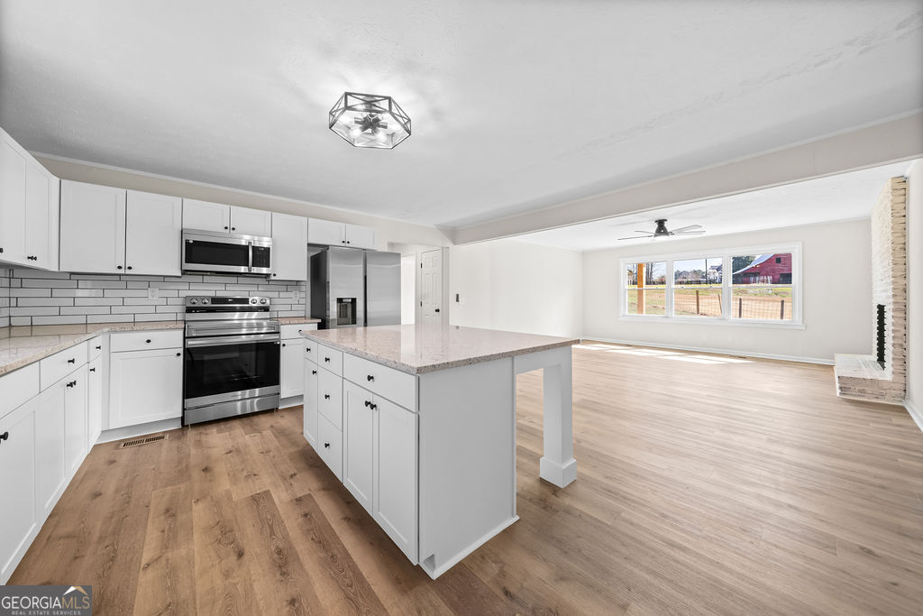 18 Holder Road Temple, GA 30179 - Photo 14 of 44 a kitchen with granite countertop a stove top oven a sink dishwasher and a refrigerator with wooden floor