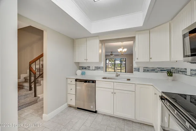 a kitchen with a refrigerator a sink and dishwasher with white cabinets