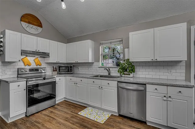 a kitchen with stainless steel appliances granite countertop a sink and cabinets