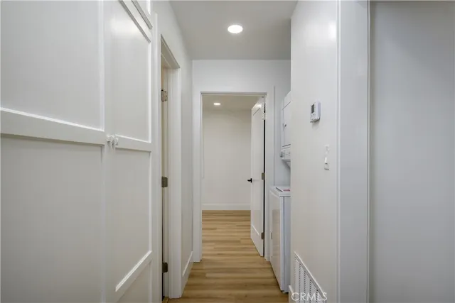 a view of a hallway with wooden floor and a bathroom