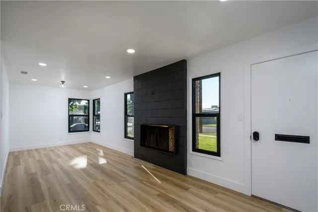 a view of an empty room with wooden floor fireplace and a window