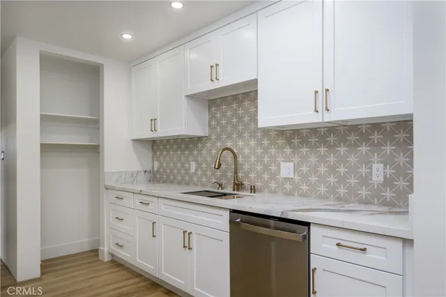 a kitchen with stainless steel appliances granite countertop a sink and a white cabinets