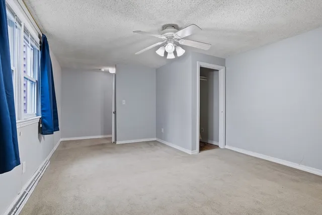 an empty room with windows and fan
