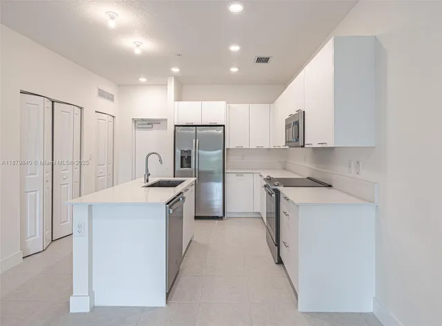 a kitchen with white cabinets and stainless steel appliances