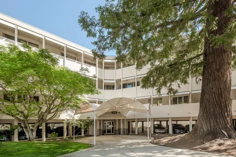 a view of a big building next to a big yard and large trees
