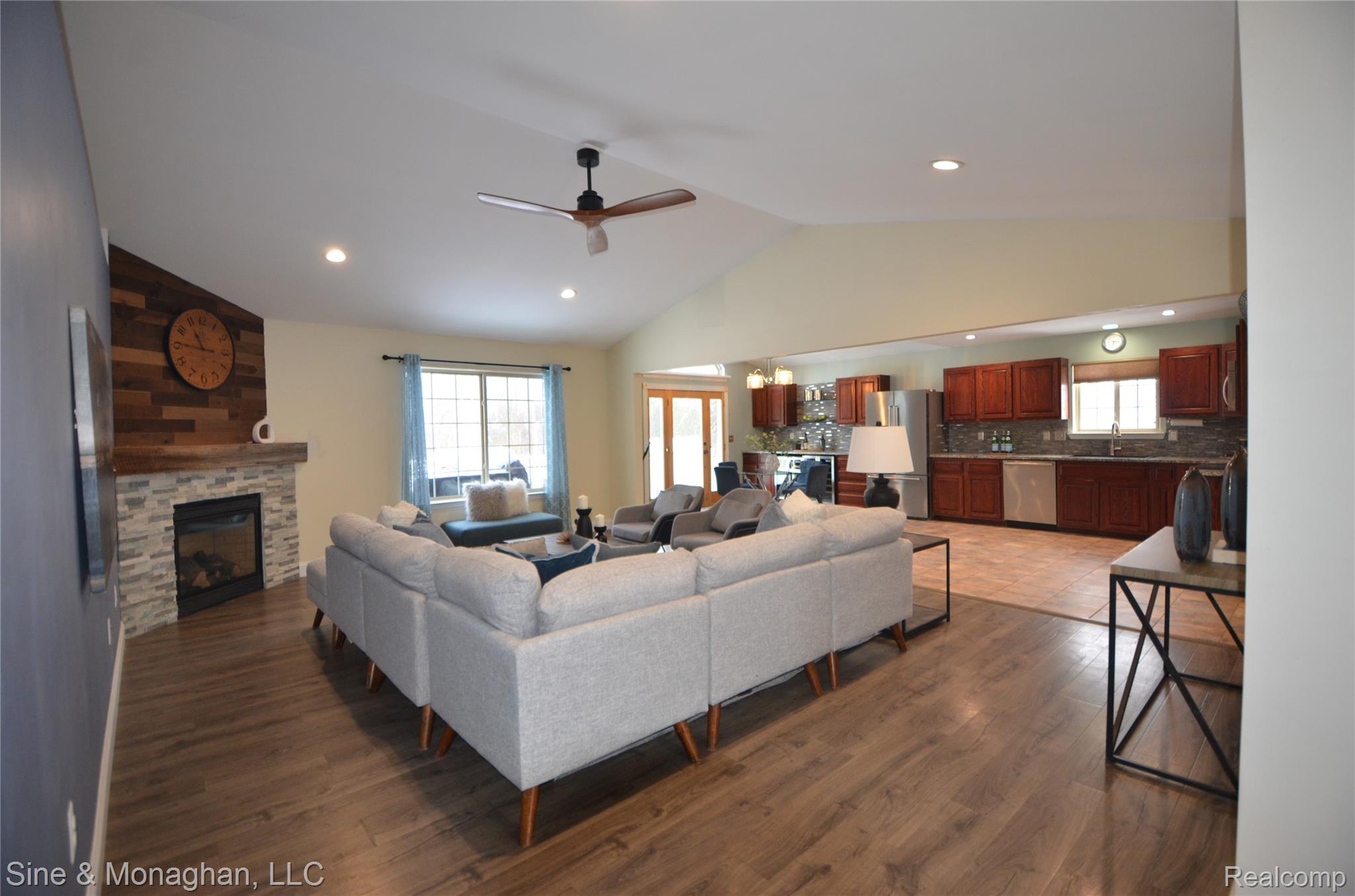 76152 Burman Road Richmond, MI 48062 - Photo 10 of 75 Living area with lofted ceiling, a fireplace, dark wood-style flooring, ceiling fan, and a chandelier