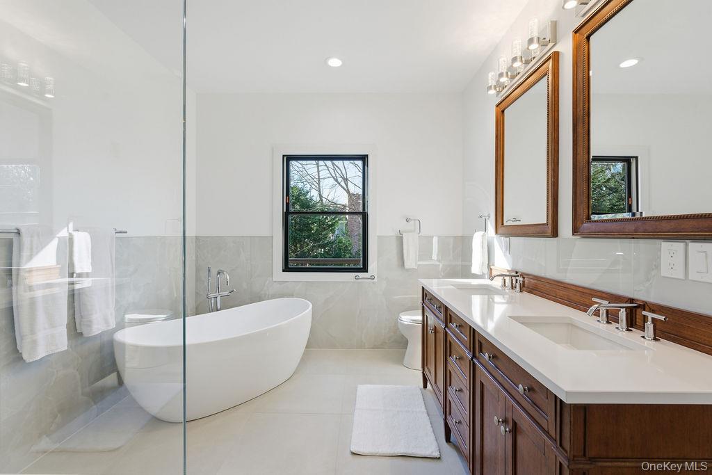768 Bridgehampton Sag Harbor Bridgehampton, NY 11932 - Photo 20 of 35 Bathroom with a freestanding tub, double vanity, light tile patterned floors, a wainscoted wall, and tile walls