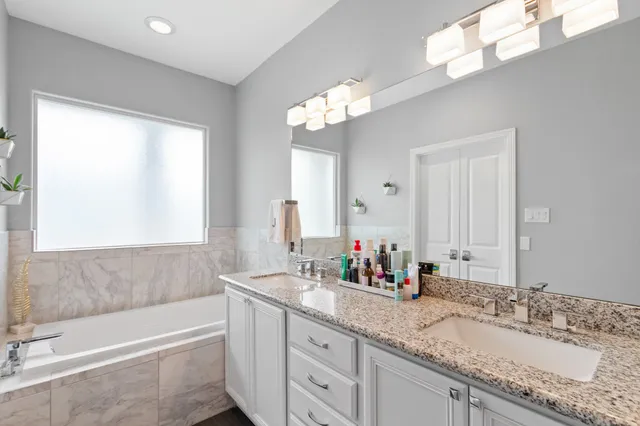 a bathroom with a granite countertop bathtub a sink and a mirror