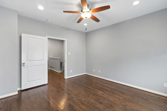 an empty room with wooden floor and a ceiling fan