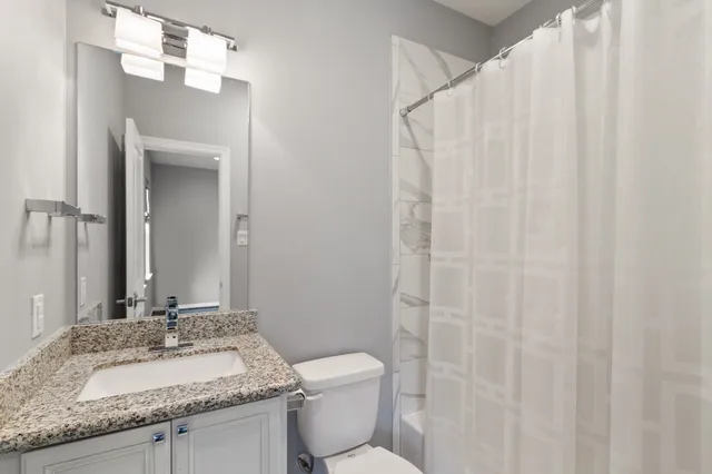 a bathroom with a granite countertop sink and a mirror with toilet