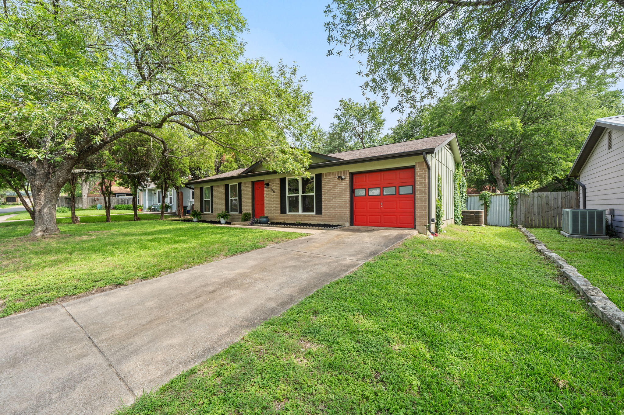 705 Dulwich Street Austin, TX 78748 - Photo 35 of 36 A well-maintained single-story home with a vibrant red garage door and mature shade trees.