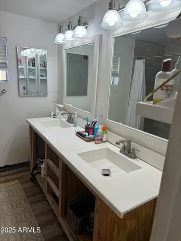 a toilet sitting next to a white sink and wooden floor