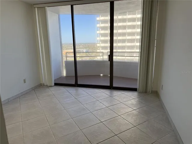 a view of a refrigerator in kitchen and an empty room