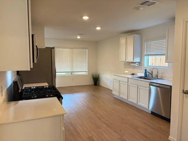 a kitchen with a refrigerator a sink wooden floor and cabinets