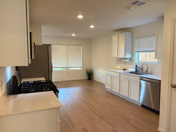 a kitchen with a refrigerator a sink wooden floor and cabinets