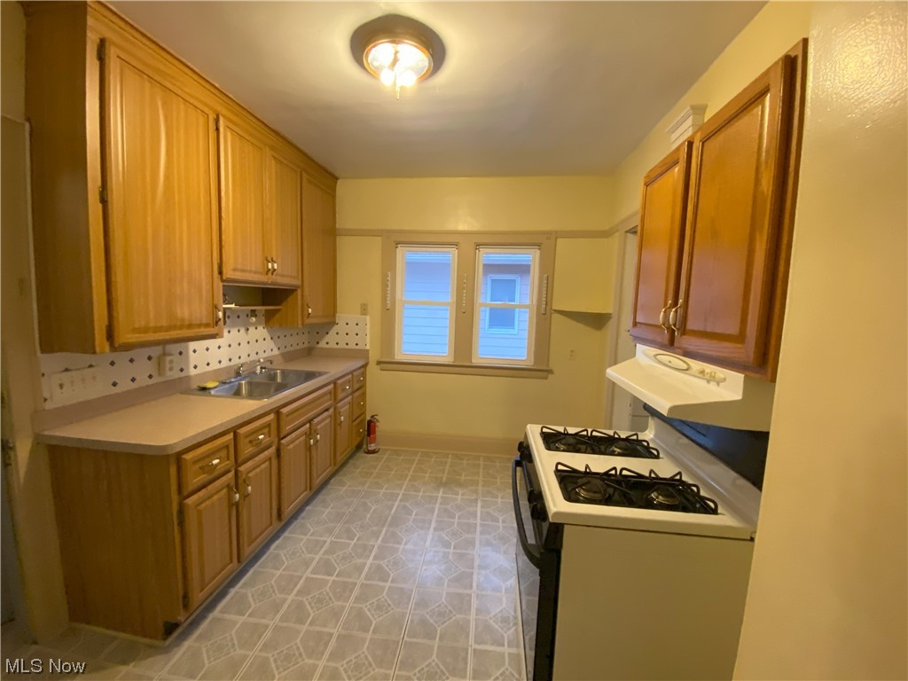 3650 Hildana Road Cleveland, OH 44120 - Photo 13 of 20 Kitchen with light tile flooring, white range with gas stovetop, sink, and backsplash