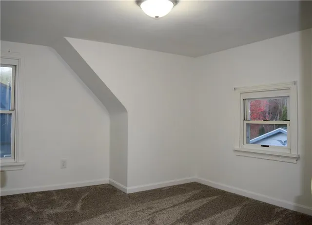an empty room with wooden floor cabinet and windows
