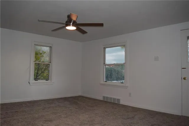 an empty room with window and ceiling fan
