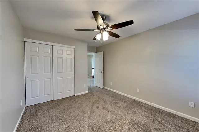 an empty room with closet and a chandelier fan