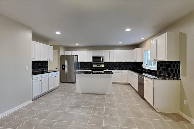 a large kitchen with kitchen island granite countertop a stove a sink a microwave and a refrigerator