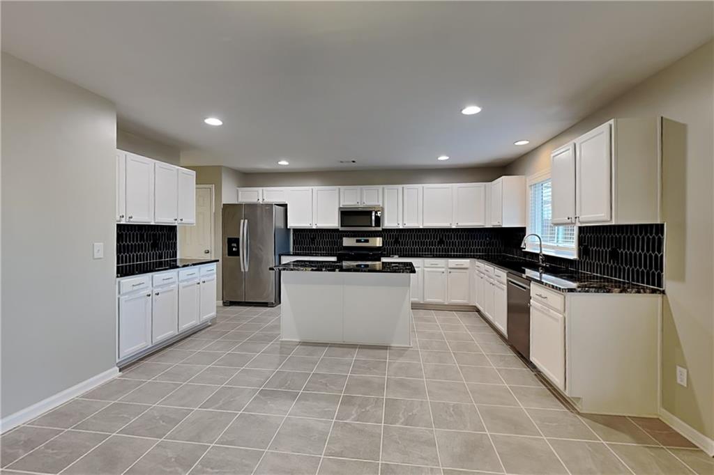 40 Parkmont Court Dallas, GA 30132 - Photo 5 of 19 a large kitchen with kitchen island granite countertop a stove a sink a microwave and a refrigerator
