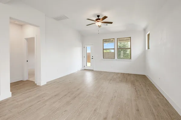a view of empty room with wooden floor and fan