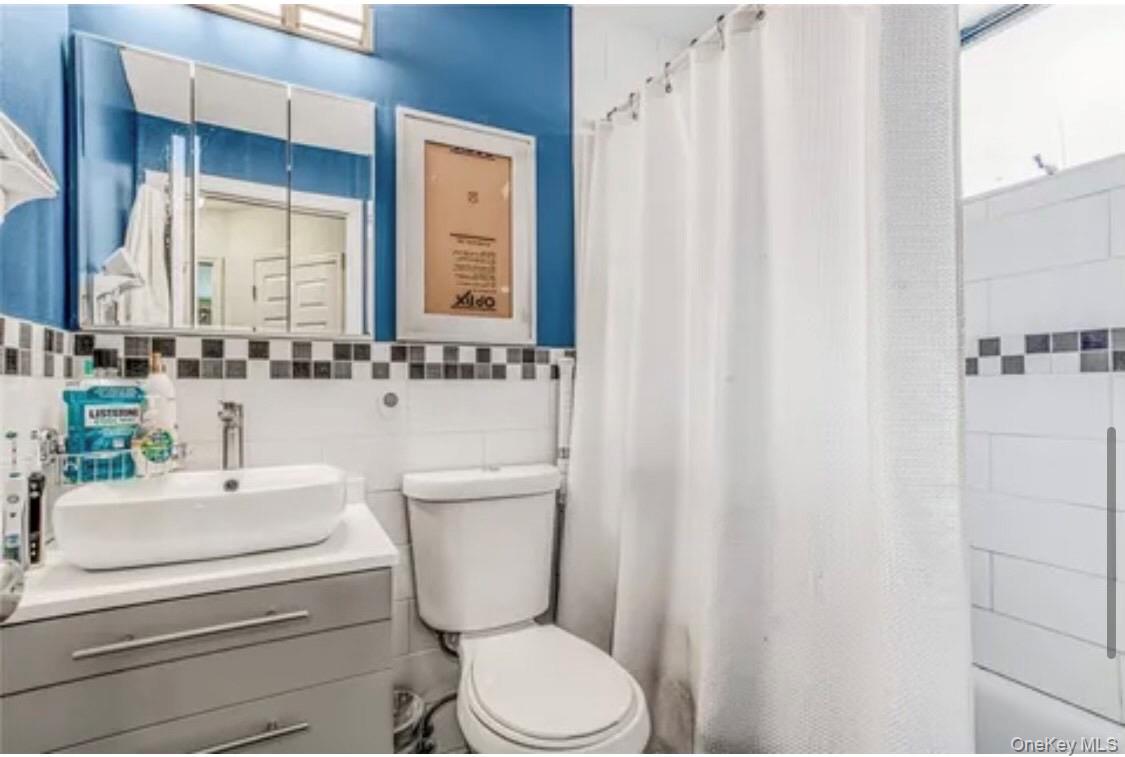 46-12 161 Street, Unit 2C Queens, NY 11358 - Photo 6 of 9 Full bath featuring vanity, tile walls, and shower / tub combo with curtain