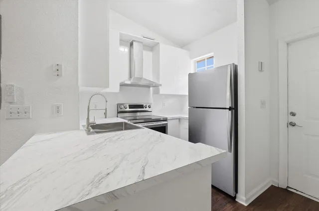 a kitchen with a refrigerator a stove and white cabinets
