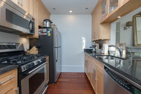 a kitchen with stainless steel appliances granite countertop a sink a stove and a refrigerator