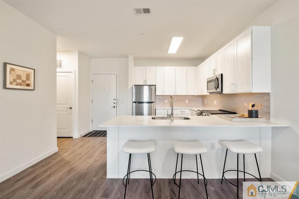 1 Nolan Way, Unit A2 North Brunswick, NJ 08902 - Photo 6 of 71 a kitchen with stainless steel appliances granite countertop a stove a sink a refrigerator white cabinets and wooden floor