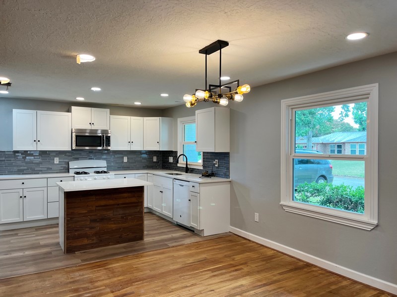 3522 Rosedale Street Houston, TX 77004 - Photo 6 of 22 a kitchen with stainless steel appliances granite countertop a stove top oven a sink dishwasher and white cabinets with wooden floor