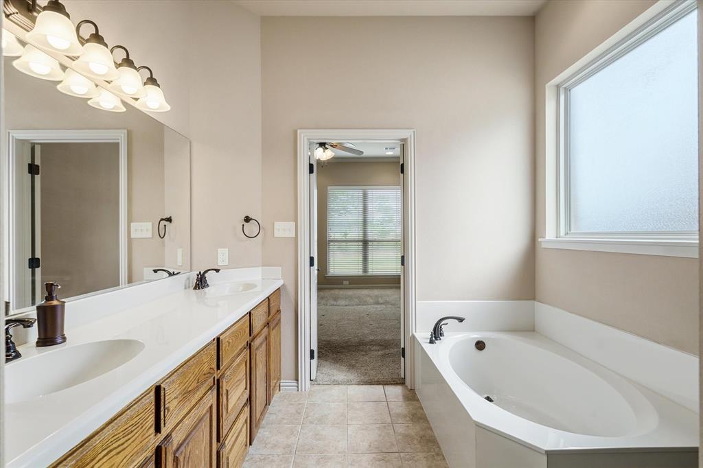 1852 Meadowview Canton, TX 75103 - Photo 16 of 28 a bathroom with a tub a double vanity sink and mirror